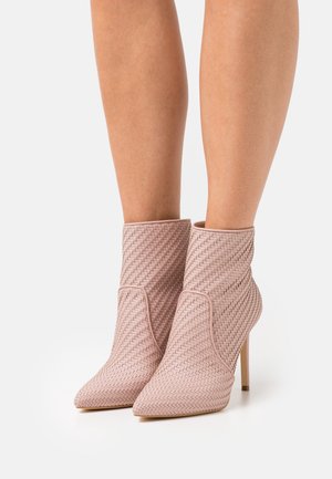 Stivaletti alla caviglia intrecciati rosa con punte appuntite e tacchi a spillo, caratterizzati da una texture liscia e un design strutturato, con cuciture decorative.