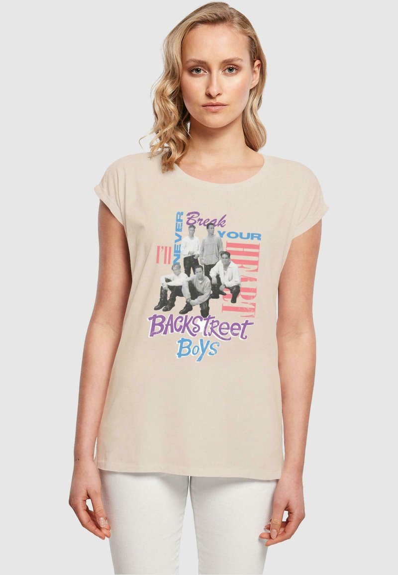 Lys beige t-skjorte med korte ermer og grafisk trykk av Backstreet Boys i svart med fargerike tekstelementer.