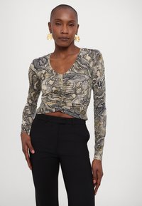 Maglietta a manica lunga con una stampa a serpente nelle tonalità beige, grigio e nero; presenta un collo a V e dettagli arricciati nella parte frontale.