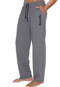 Graue, lockere Sweatpants aus weichem Material; mit einem schwarzen Logo auf der linken Seite und einem verstellbaren Kordelzugbund.