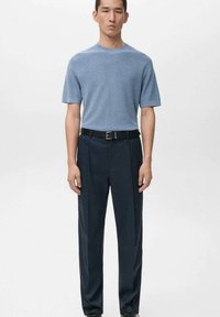 Světlomodré krátké pletené tričko v kombinaci s tmavě modrými kalhotami, s hladkou texturou a černým páskem s kovovou sponou.