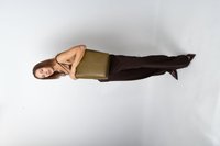 Grøn håndtaske med krokodillepræg, rektangulær form, glat tekstur, holdt op mod en neutral baggrund. Model iført brunt outfit og høje hæle.