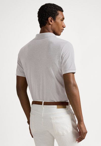 Γκρι πόλο μπλούζα με υφή, κοντά μανίκια και κλασικό γιακά, συνδυασμένη με λευκά παντελόνια και καφέ δερμάτινη ζώνη.