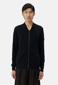 Svart zip-up cardigan, stickad tyg, ribbade muddar och nederkant, framfickor, minimalistisk design. Slim fit med ståkrage.