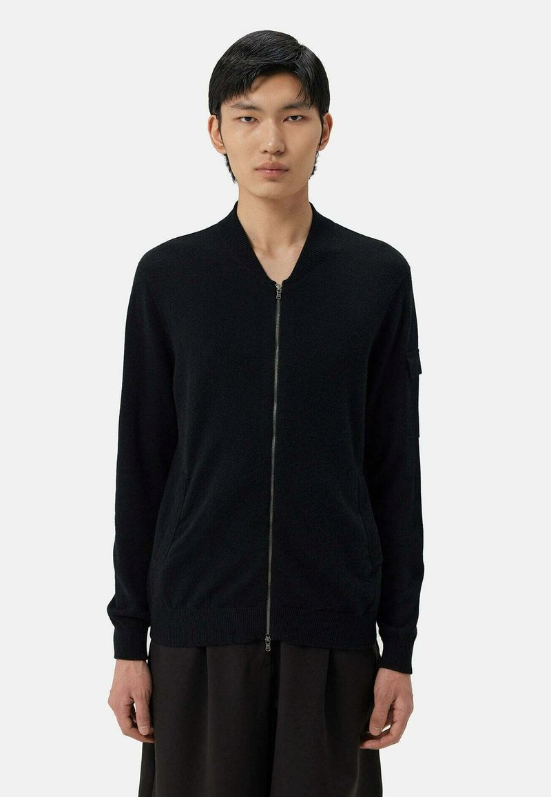 Svart zip-up cardigan, stickad tyg, ribbade muddar och nederkant, framfickor, minimalistisk design. Slim fit med ståkrage.