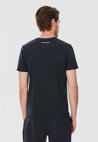 Czarna bawełniana koszulka z krótkim rękawem, z okrągłym dekoltem i detalem z logo na plecach. Gładka tekstura, standardowy krój.