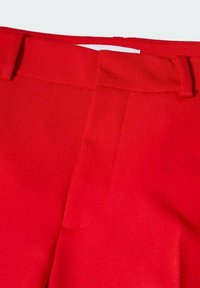 Pantalons ajustés rouges en tissu lisse, avec une taille structurée et des passants de ceinture. L'avant présente un détail de couture subtil et pas de poches.