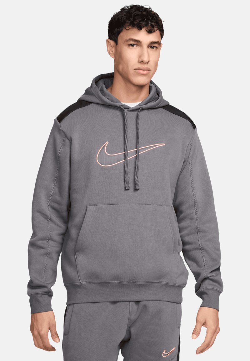 Felpa grigia con tasca a marsupio, dettagli neri sulle spalle e logo Nike rosa sul petto. Realizzata in tessuto morbido e strutturato.