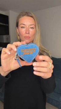 Breloc în formă de inimă din denim albastru, cu "tommy jeans" brodat în portocaliu. Are o clemă argintie și o buclă albastră pentru atașare.