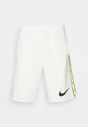 Witte Nike shorts met een elastische tailleband, zijzakken, zwart logo aan de voorkant en een neongroene accentstreep langs de zijkanten.