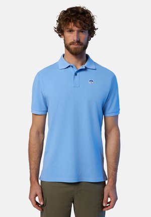 Polo shirt azzurro chiaro realizzato in morbido cotone, con una placca a tre bottoni e un piccolo logo rotondo sul lato sinistro del petto. Maniche corte.