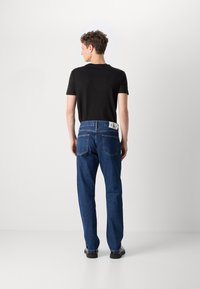 Sinine denimist teksad, lõdva istumisega, nähtava õmblusega ja kahe tagataskuga. Ühendatud musta lühikeste varrukatega särgiga.