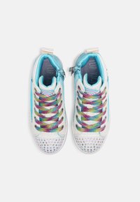 Färggranna sneakers med en iriserande finish, regnbågsmönstrade snören och en glänsande tåbox prydd med rhinestones.