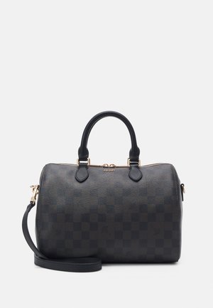 Sac à main en cuir noir avec motif à carreaux, double poignée, fermeture éclair dorée et bandoulière amovible, placé sur un fond blanc.