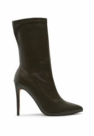Czarna skórzana botka do połowy łydki na szpilce z ostrym czubkiem i smukłym wysokim obcasem, na białym tle.