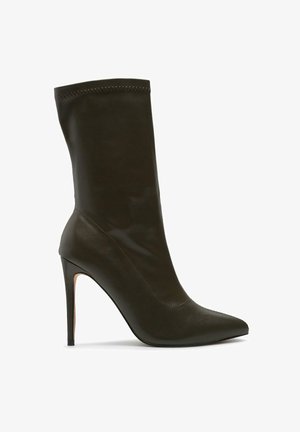 Schwarzer, bis zur Mitte der Wade reichender Stiletto-Stiefel aus Leder mit spitzer Kappe und schlankem hohen Absatz, isoliert vor weißem Hintergrund.