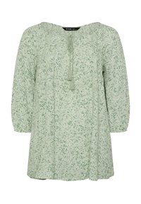 Ljusgrön blus i tyg med blommönster. Har rund halsringning, samlade ärmar och en knytdetalj vid halsringningen.