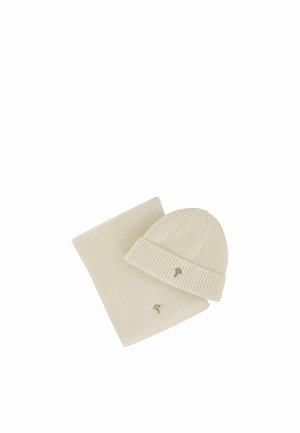 Cream-colored ribbed knit hat and matching scarf, each with a small gold tree-shaped emblem on a white background.