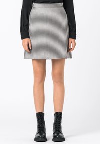 Svart och vit houndstooth kjol med en utsvängd silhuett, med hög midja och en mjuk textur, i kombination med svarta snörboots.