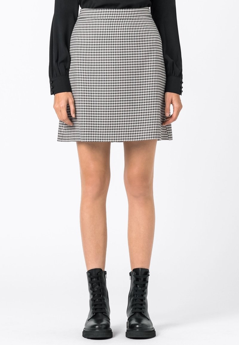 Svart och vit houndstooth kjol med en utsvängd silhuett, med hög midja och en mjuk textur, i kombination med svarta snörboots.