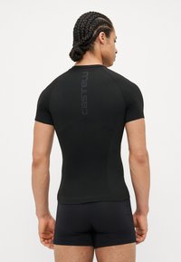 Schwarzes, enganliegendes kurzärmeliges Sportshirt mit glatter Textur und vertikalem Logo-Detail auf dem Rücken. Minimalistisches Design.