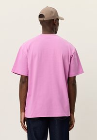 Ροζ βαμβακερό T-shirt με άνετη εφαρμογή, κοντά μανίκια και λαιμόκοψη στρογγυλή, με λεία υφή και ελαφρώς μακρύτερο πίσω στρίφωμα.