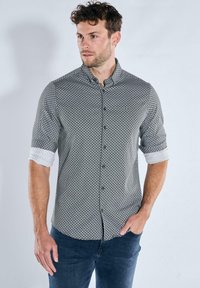 Hemdenhemd in Schwarz-Weiß mit einem geometrischen Muster, hochgekrempelten Ärmeln mit festem weißem Manschettenabschluss und einem schlanken Schnitt.