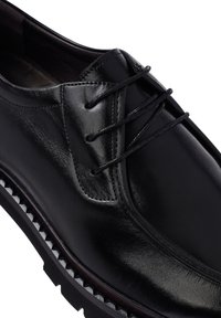 Zwarte leren dresschoenen met een gladde afwerking, vetersluiting, ronde neus en een gekarteld rubberen zool voor grip.