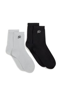 Deux paires de chaussettes de cheville, une grise claire et une noire, chacune avec un petit logo brodé contrastant près de la cheville.