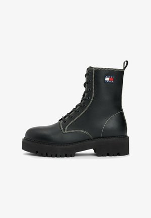 Czarne skórzane buty za kostkę na sznurówki z grubą podeszwą, białym przeszyciem, pętelką oraz naszywką z logo Tommy Jeans po boku.