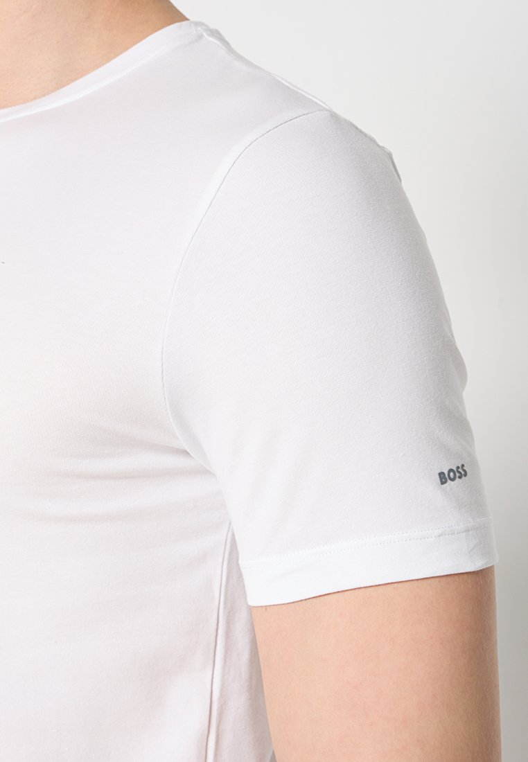 Weißes Kurzarm-T-Shirt aus weicher Baumwolle. Verfügt über einen Rundhalsausschnitt und ein kleines "BOSS"-Logo in Grau, das auf der linken Schulter aufgedruckt ist.