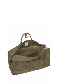 Sac de sport en khaki avec des accents en cuir, fermoir à glissière et un intérieur spacieux avec un revêtement beige et une petite poche.