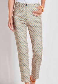 Pantaloni a fantasia con un design geometrico in arancione chiaro, blu e crema. Tessuto morbido con vestibilità slim e cintura standard.