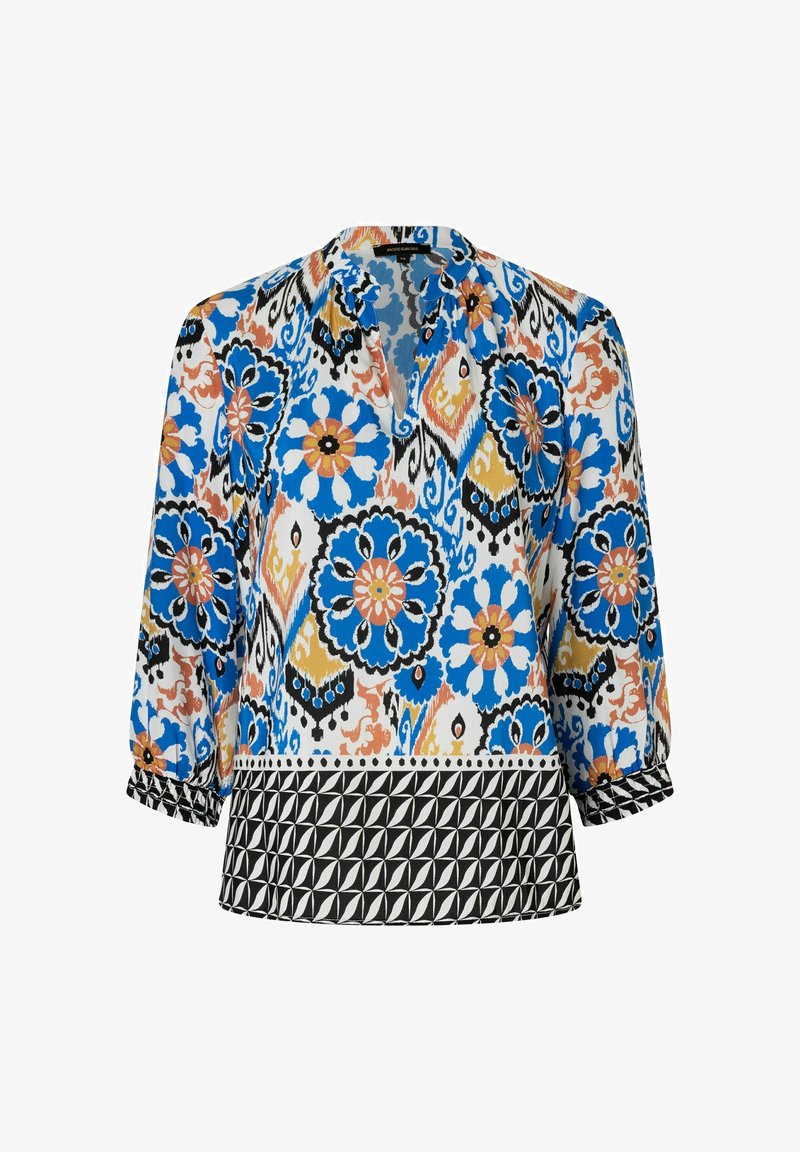 Bunt gemusterte Bluse mit floralen Motiven in Blau, Orange und Schwarz, mit Dreiviertelärmeln und einem schwarzen geometrischen Band am Saum.