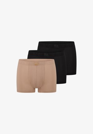 Tre par herreboxershorts i ensfarvede farver, én beige foran og to sorte bagved, arrangeret side om side.