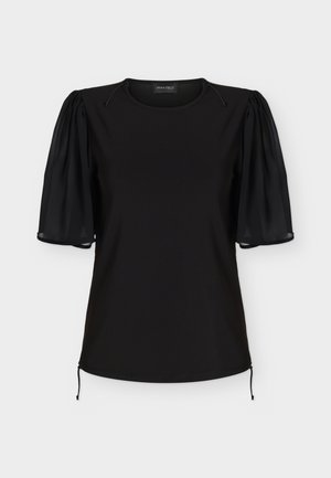 Blouse noire à manches courtes avec manches bouffantes en tissu transparent, encolure ronde et détails à cordons aux épaules et à l’ourlet.