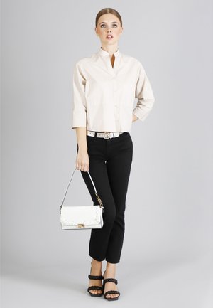 Beige beskåret skjorte med knapper og stående krave, sorte slim-fit jeans, hvid håndtaske med rynket design og sorte platform sandaler.