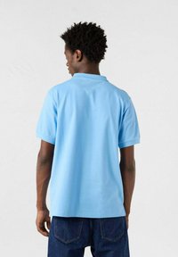 Polo shirt in cotone azzurro chiaro con maniche corte e colletto classico, caratterizzato da una texture morbida e una vestibilità comoda.