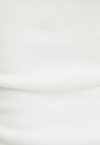 Vit ribbad tyg med en slät yta. Materialet visar fina horisontella linjer och är något elastiskt, vilket gör det idealiskt för åtsittande mönster.