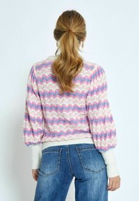 Wollen sweater in een mix van stoffen met een zigzagpatroon in roze en blauw, met pofmouwen en een witte geribbelde onderrand en manchetten. Achteraanzicht weergegeven.