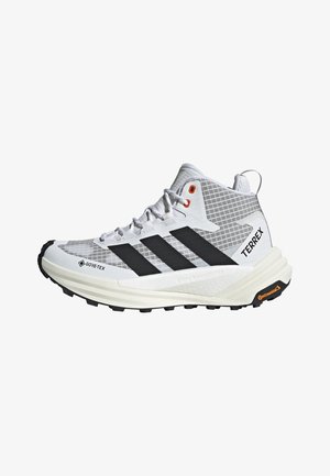 Weißer und grauer High-Top Adidas Terrex Trailschuh mit schwarzen Streifen, Gore-Tex Obermaterial und Continental Gummisohle.