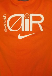 Orange cotton t-shirt featuring bold white text "swoosh" and "AIR" with a basketball icon, and a white Nike logo at the bottom.