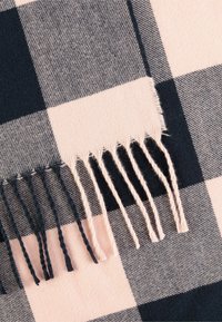 Gewebte Karodecke mit abwechselnd hellrosa und dunkelgrauen Quadraten. Mit Fransenrändern aus gedrehtem Garn. Weiche Textur, warmer Stoff.