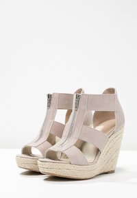 Sandali con zeppa in suede beige, dotati di chiusura con zip e lati a taglio, montati su un tacco a zeppa avvolto in juta.