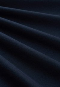 Donker marineblauwe stof met een gladde textuur, gekenmerkt door duidelijke zachte plooien en een matte afwerking, die subtiele kleur- en dieptevariaties toont.