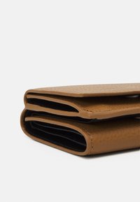 Brauner, strukturierten Leder-Geldbeutel mit Überschlagklappe, ausgestattet mit schwarzem Innenfutter und flachen Fächern für Karten oder Bargeld.