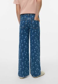 Mėlyni plataus modelio džinsai su gėlių raštu, penkių kišenių dizainu ir vidutinio aukščio liemeniu. Audinys šiek tiek tekstūruotas.