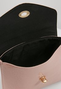 Pink faux leather bag with a crocodile texture, gold hardware, and a black fabric interior. The flap has a small gold fastener.