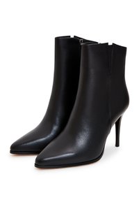 Musta nahkainen nilkkabootsi, jossa on terävä kärki, kapea stiletto-korko ja minimalistinen muotoilu. Varustettu sivuvetoketjulla, joka helpottaa pukemista.