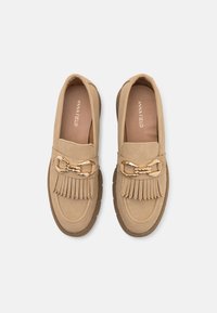 Brune semskede loafers med en dekorativ gullkjedeakzent og frynser foran. Flatt, teksturert gummisåle.
